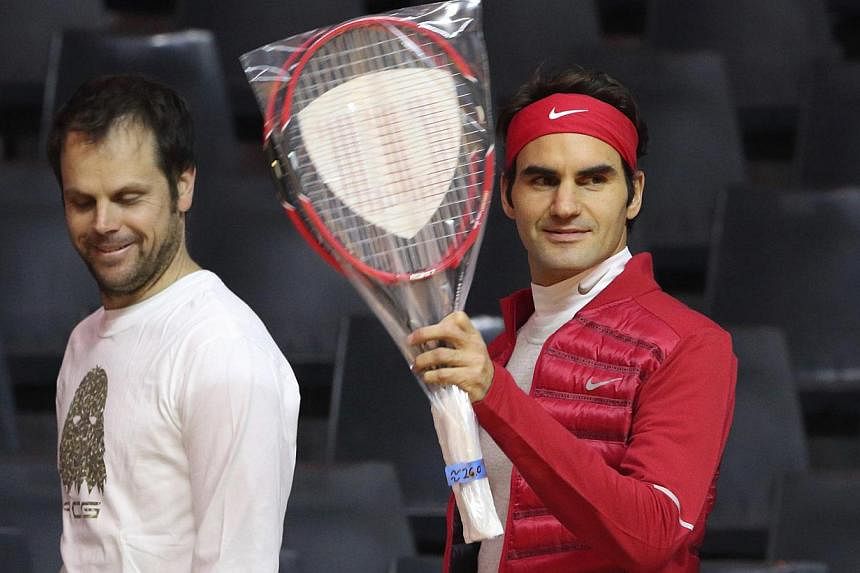 Roger Federer of Switzerland (right) waves as he arrives with Swiss captain Severin Luthi during a Davis Cup tennis training session at the Pierre Mauroy stadium in Villeneuve d'Ascq, northern France, Nov 19, 2014. France will face Switzerland in the