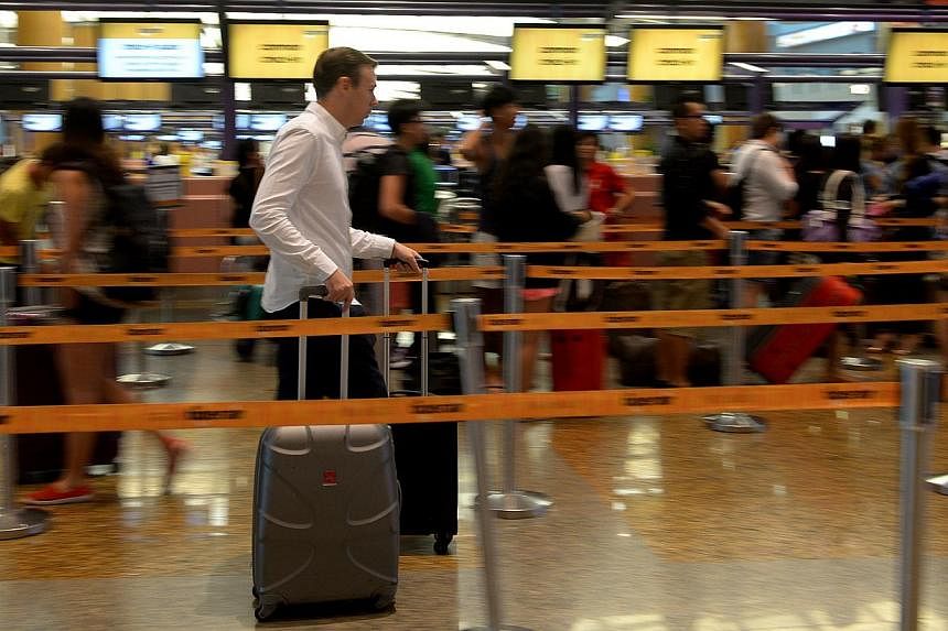 Travellers at a check-in counter at Changi Airport's Terminal 2 on Oct 29, 2014. -- PHOTO: ST FILE