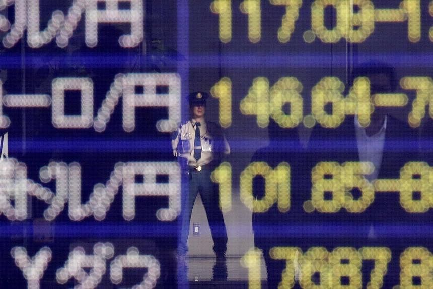 A security worker is reflected in an electronic board showing the exchange rates between the Japanese yen against the US dollar, the euro, and Australian dollar, and market indices of Dow Jones, outside a brokerage in Tokyo, on Nov 19, 2014. -- PHOTO