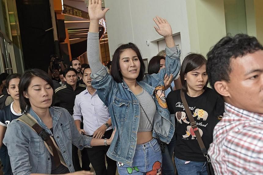 A Thai student (centre) holding her arms up as she is escorted out of a cinema hall by plainclothes police officers in Bangkok on Nov 20, 2014. Political protests are banned under martial law, but that has not stopped some university students from st