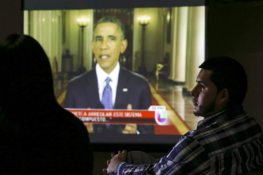 A group of legal and undocumented immigrants watch US President Barack Obama speaking about the country's immigration policy during a nationally televised address from the White House in Washington, on a screen in New Brunswick, New Jersey on Nov 20,