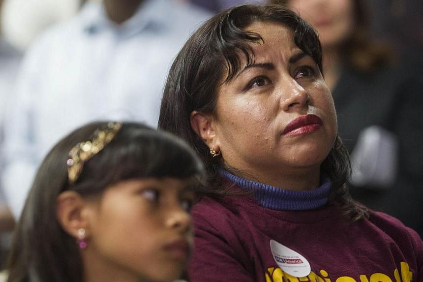 In Los Angeles, California, Nancy Catano, 41, a non-US citizen, and her daughter Michelle, 9, watch US President Barack Obama's nationally televised announcement on immigration reform on Nov 20, 2014. -- PHOTO: AFP&nbsp;