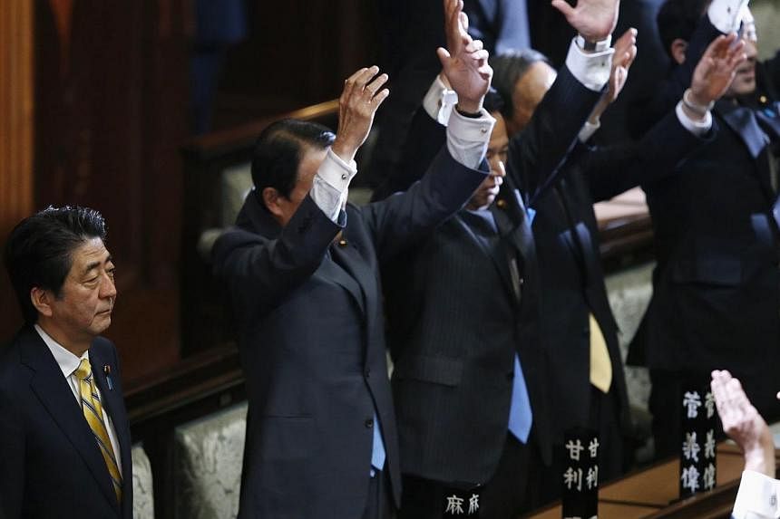 Japan's Prime Minister Shinzo Abe (2nd left) stands next his cabinet ministers as they raise their hands and shouts "banzai" (cheers) after the dissolution of lower house was announced at the Parliament in Tokyo Nov 21, 2014.&nbsp;