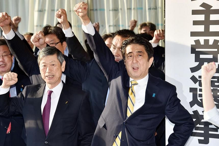 Japan's Prime Minister and leader of the ruling Liberal Democratic Party (LDP) Shinzo Abe (centre, right) raises his fist in the air to shout with his party's lawmakers as they open an election campaign office at the LDP headquarters in Tokyo on Nov 