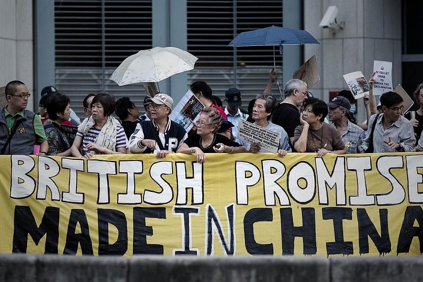 Pro-democracy protesters stand behind a banner as they stage an occupy protest outside the British consulate in the Admiralty district of Hong Kong on Nov 21, 2014.&nbsp;A small group of protesters gathered outside Hong Kong's British consulate on Fr