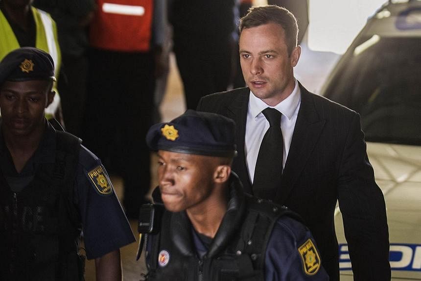 South African Paralympian athlete Oscar Pistorius (centre) is escorted to a police vehicle to be transported to prison following his sentencing at the High Court in Pretoria on Oct 21, 2014.&nbsp;Oscar Pistorius, serving a five-year jail sentence for