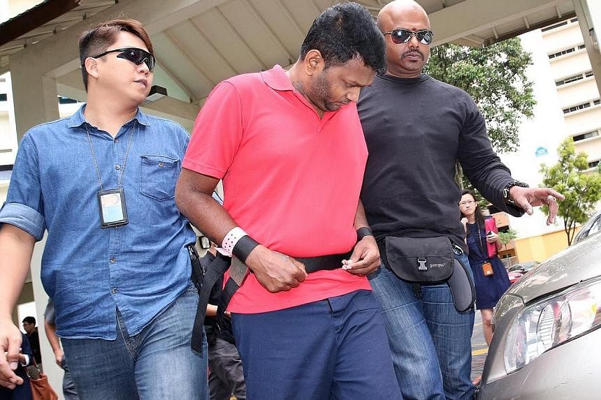 Annadurai Raman (in red) at Block 125 Geylang East Avenue 1 on Nov 18, 2014, where he took part in a crime scene reenactment. Annadurai, the first man to be charged over the brazen robbery of a money changer, has been remanded in prison after failing