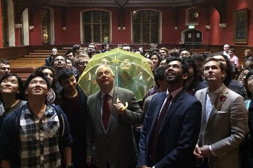Hong Kong's last British governor, Lord Chris Patten, holding a yellow umbrella - a symbol of the Occupy movement in Hong Kong - given to him by a student in the audience at an Oxford University event. Mr Patten urged nations to stand up to China ove