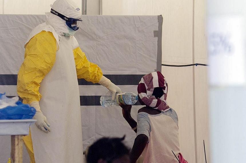 A nurse wearing a personal protective equipment assists a patient at the Ebola treatment centre run by the French Red Cross society in Macenta in Guinea on Nov 20, 2014.&nbsp;US regulators on Thursday suspended trading in four small over-the-counter 