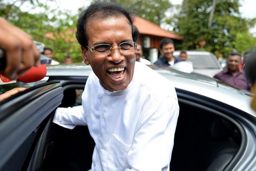 Sri Lanka's Health Minister Maithripala Sirisena smiles as he speaks with health workers in Colombo on Nov 21, 2014, while leaving a meeting marking the recruitment of new employees. -- PHOTO: AFP