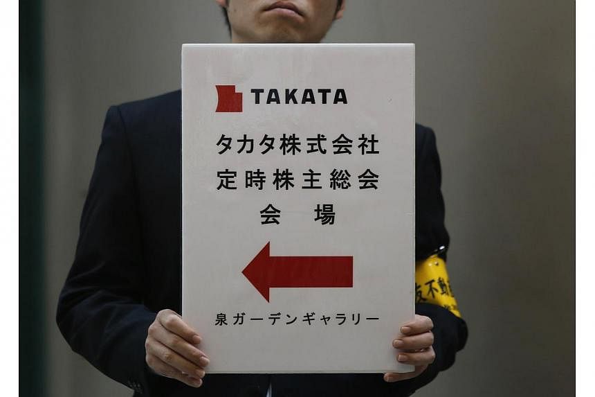 An employee of Japanese auto parts maker Takata Corp holds a sign board of the company's Annual General Meeting at an exit of a station near the venue in Tokyo on June 26, 2014. Japan's Transport Minister said on Friday that he had directed Takata Co
