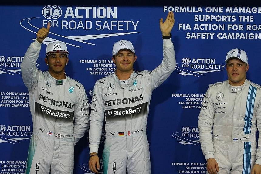 Mercedes drivers Nico Rosberg (centre) and Lewis Hamilton (left) and Williams driver Valtteri Bottas celebrate after the qualifying session at the Yas Marina circuit in Abu Dhabi on Nov 22, 2014, ahead of the Abu Dhabi Formula One Grand Prix. -- PHOT