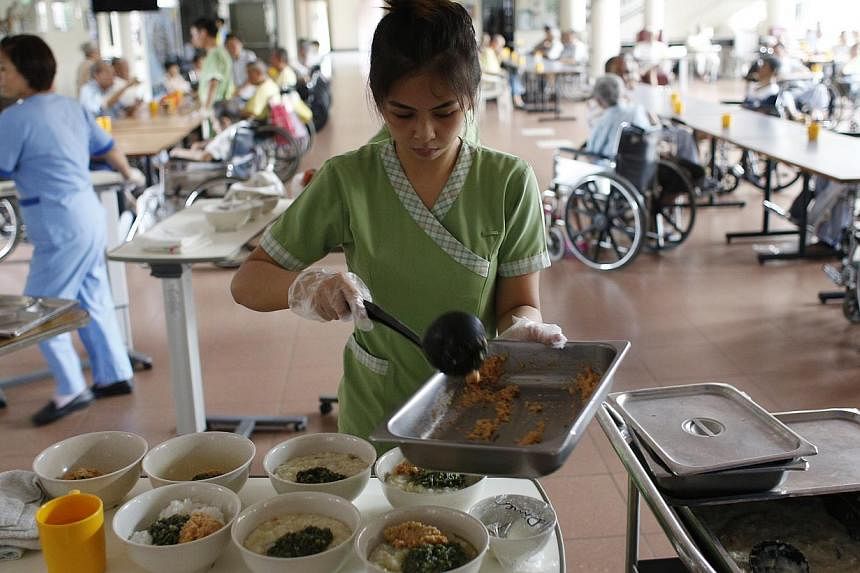 Swami Home's head chef, Mr Song Wee Kiat (above, left), and his colleague, Mr Mohammed Monirul, serve dinner while nurse aide Suzanne Ebuenga (below) fills up bowls of porridge for patients.