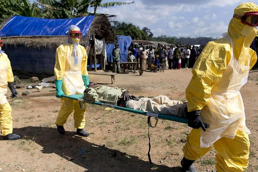 Health workers wearing protective suits carry a patient suspected of having Ebola on their way to an Ebola treatment centre run by the French Red Cross in Macenta on Nov 21, 2014. The World Health Organisation said Friday that 5,459 people had so far