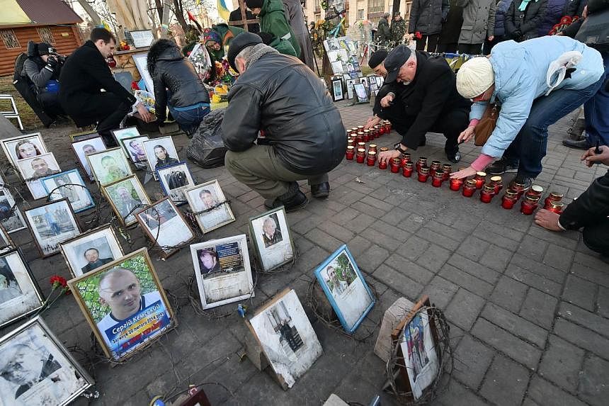 People set candles during a memorial ceremony in Kiev on Nov 21, 2014. Dozens of people gathered at the iconic Independence Square, known locally as Maidan, laying flowers at shrines to the more than 100 people who died in protests that started on No