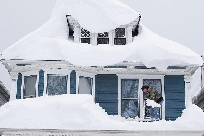 Tom Wilczak shovels snow from the roof of his home following a storm in Buffalo, New York Nov 20, 2014. The death toll rose to 13 on Friday from a rare pre-winter snowstorm in western New York state where rising temperatures and heavy weekend rain is