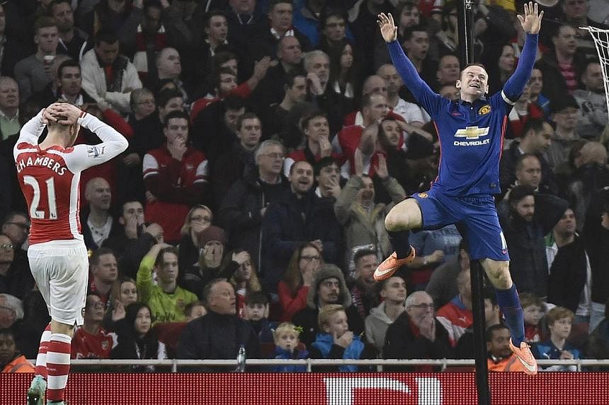 Manchester United's Wayne Rooney (right) celebrates an own goal by Arsenal's Kieran Gibbs during their English Premier League match at the Emirates Stadium in London on Nov 22, 2014. -- PHOTO: REUTERS