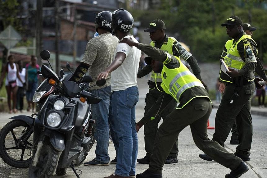 A Colombian police officer frisks a motorcyclist in Quibdo, Department of Choco, Colombia, on Nov 21, 2014. FARC guerillas who captured a Colombian general and four other people will release them next week, president Juan Manuel Santos said on Saturd
