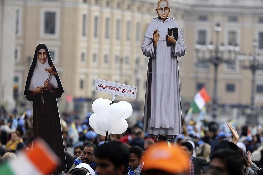 Faithful hold cut-outs of new Indian saints Kuriakose Elias Chavara (right) and Mother Euphrasia Eluvathingal before a canonisation ceremony led by Pope Francis, to make saints out of six men and women, in Saint Peter's square at the Vatican on Novem