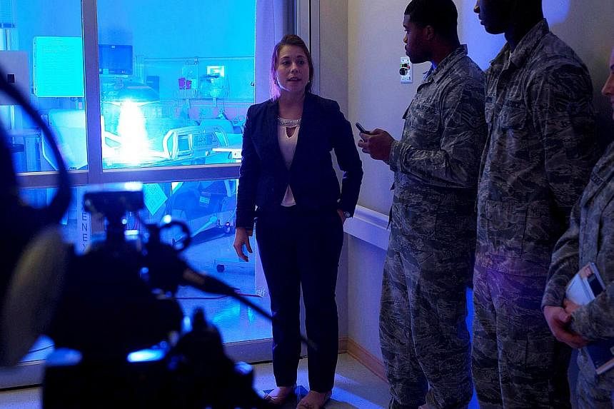 This US Air Force photo obtained on November 22, 2014 shows Geri Genant (left), as she demonstrates the capabilities of “Saul”, a germ-zapping robot, to airmen in this October 20, 2014 photo, at Joint Base Langley-Eustis, Virginia. -- PHOTO: AFP