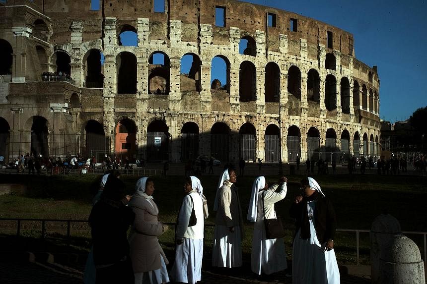 Nuns take pictures of the Colosseum at sunset on Nov 21, 2014 in Rome. A Russian tourist caught red-handed trying to carve his initials on a wall of Rome's Colosseum was ordered Saturday to pay a fine of €20,000 (S$32,200), Ansa reported. -- PHOTO: