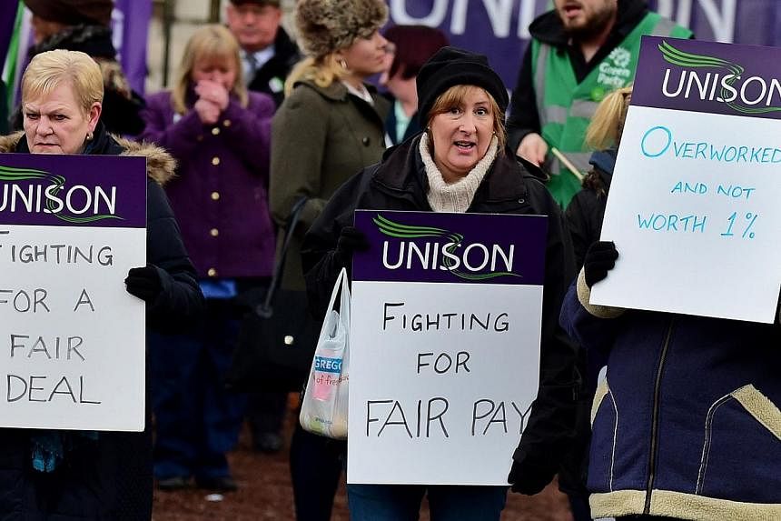 Health workers demonstrate as they take part in a four-hour strike outside the Manchester Royal Infirmary in north-west England on Nov 24, 2014. -- PHOTO: AFP