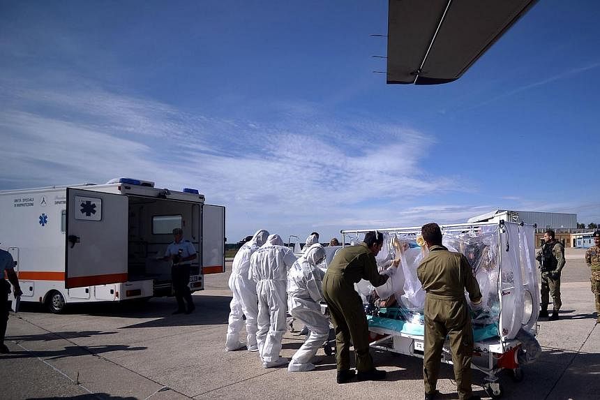 Italian aeronautical personnel wearing protective suits take care of a pretended Ebola victim during a specialized training course for the management and transport of highly contagious patients, in Rome's Pratica di Mare military airport in Pomezia. 