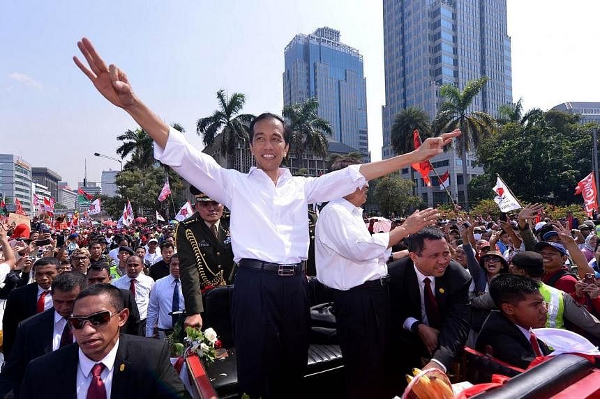 In this handout picture taken and released on Oct 20, 2014 by the presidential palace Indonesian President Joko Widodo (left) and vice President Jusuf Kalla (right) wave to supporters from a horse drawn carriage while the motorcade makes its way thro
