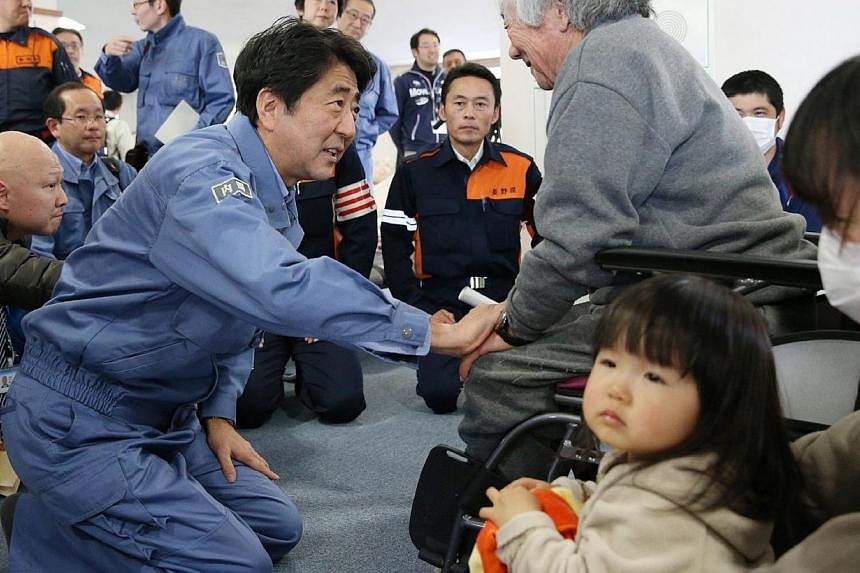 Japanese Prime Minister Shinzo Abe (left) expresses sympathy to victims of earthquake as he visits a shelter at Hakuba village in Nagano prefecture, central Japan on Nov 24, 2014.&nbsp;Mr Abe on Monday promised "firm" support after meeting victims of