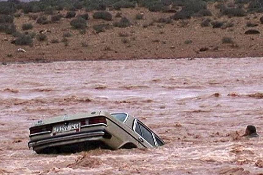 A driver and his car are stranded in flood waters Nov 22, &nbsp;2014 in the southern region of Ouarzazate in Morocco. -- PHOTO: AFP