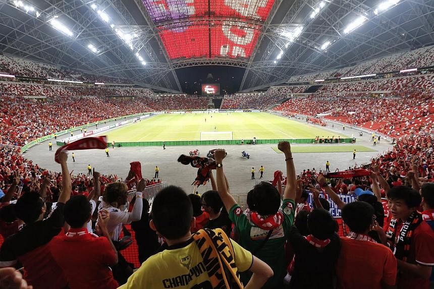Fans cheering as Singapore scores an equaliser against Thailand in the AFF Suzuki Cup match at the new National Stadium last night.