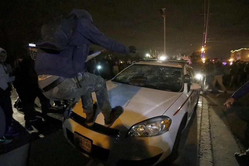 Protesters vandalise a car outside the Ferguson Police Department in Ferguson, Missouri, after a grand jury returned no indictment in the shooting of Michael Brown Nov 24, 2014. -- PHOTO: REUTERS