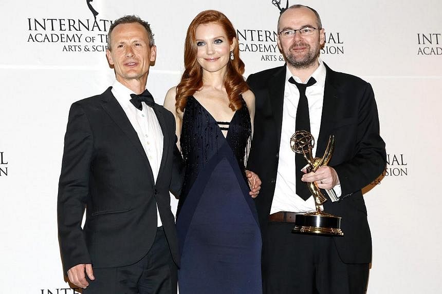 Director Marc Munden (left) and writer/creator and executive producer Dennis Kelly of British crime television series Utopia, backstage with their award for Drama Series, with actress Darby Stanchfield at the 42nd International Emmy Awards in New Yor