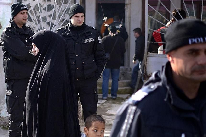 Policemen stand guard, during a search operation of a house in the Roma suburb in the city of Pazardjik, South West Bulgaria on Nov 25, 2014.&nbsp;Bulgarian authorities raided a mosque in the south of the country Tuesday as part of a probe into a loc