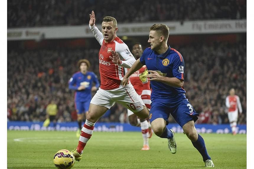 Manchester United's Luke Shaw (right) is challenged by Arsenal's Jack Wilshere during their English Premier League football match at the Emirates Stadium in London on Nov 22, 2014.&nbsp;-- PHOTO: REUTERS