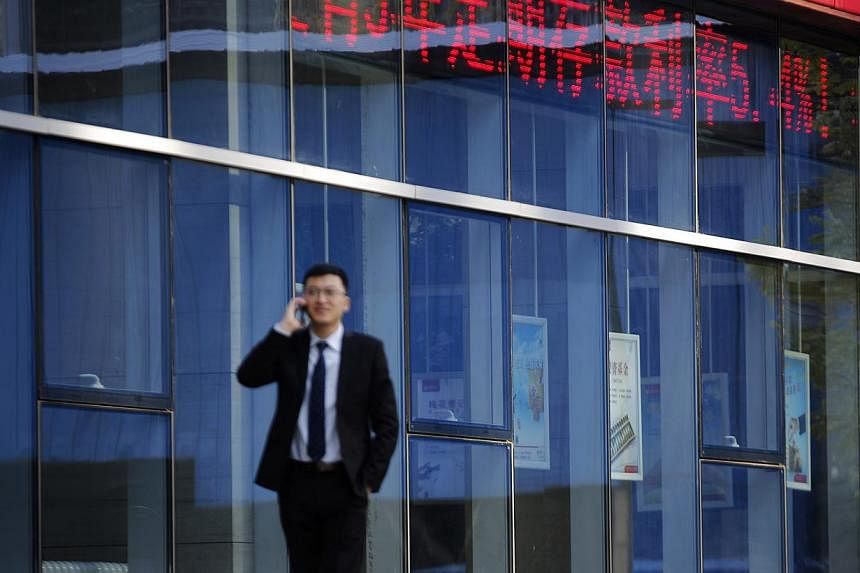 A man on Nov 24 talking on a phone in front of a Beijing commercial bank whose &nbsp;display board shows the interest rate for fixed deposits. China's central bank cut &nbsp;the yield for a key short-term money rate on Nov 25, following a surprise cu