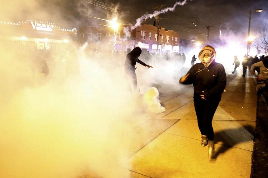 Protesters run from a cloud of tear gas after a grand jury returned no indictment in the shooting of Michael Brown in Ferguson, Missouri, on Nov 24, 2014. -- PHOTO: REUTERS
