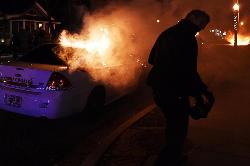 Protesters set police cars on fire during clashes following the grand jury decision in the death of 18-year-old Michael Brown in Ferguson, Missouri, on Nov 24, 2014. -- PHOTO: AFP
