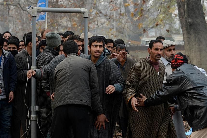 Plain-clothed Indian police personnel search Kashmiri supporters as they arrive for an election rally by the newly launched Peoples Republician Party (PRP) in Srinagar on Nov 24, 2014. -- PHOTO: AFP