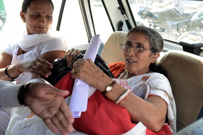 Indian Prime Minister Narendra Modi's wife, Ms Jashodaben (right), seated next to an unidentified woman, holding a copy of the Right To Information (RTI) application filed by her as she leaves the Deputy Superintendent of Police (DSP) office in Mehsa