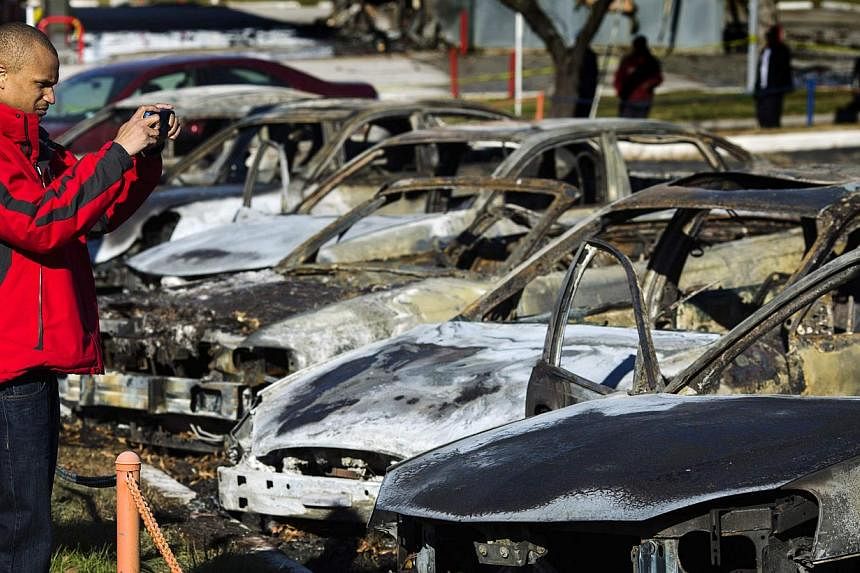 A man stops to take a photograph of burned and damaged cars following a night of rioting in Ferguson, Missouri, on Nov 25, 2014. -- PHOTO: REUTERS&nbsp;
