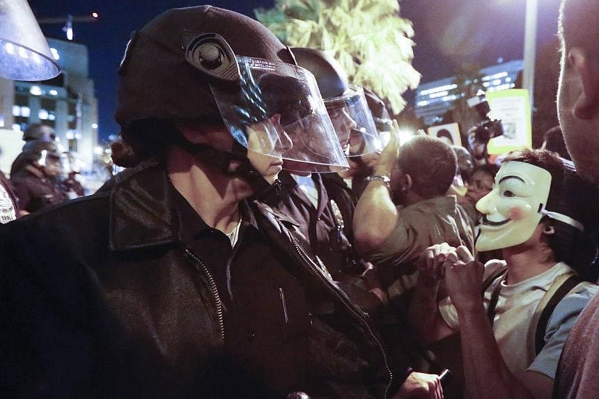 Protesters face off against a line of police during a demonstration outside LAPD headquarters in Los Angeles, California, following the Monday grand jury decision in the shooting of Michael Brown in Ferguson, Missouri, on Nov 25, 2014. -- PHOTO: REUT