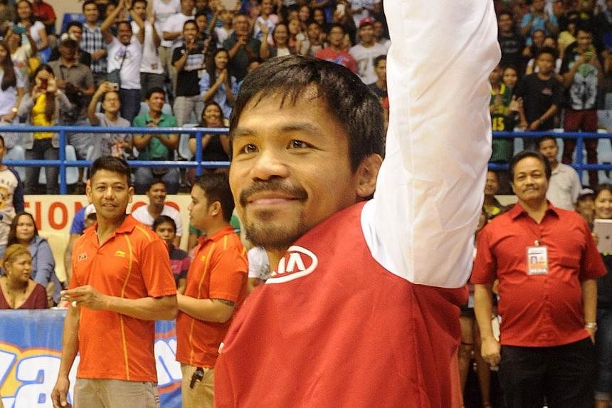 World boxing champion Manny Pacquiao waves to fans before taking part in a basketball game in Manila on Nov 26, 2014. Pacquiao resumed his Philippine pro basketball career on Wednesday with a crushing defeat that extended his team's losing streak to 