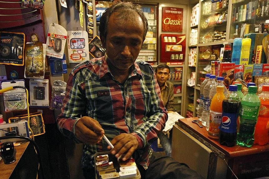 A shopkeeper takes out a cigarette from a box for a customer in Kolkata on Oct 15, 2014.&nbsp;Health campaigners on Wednesday welcomed India's plans to raise the age for tobacco purchases to 25 and ban unpackaged cigarettes, hailing them as a major s