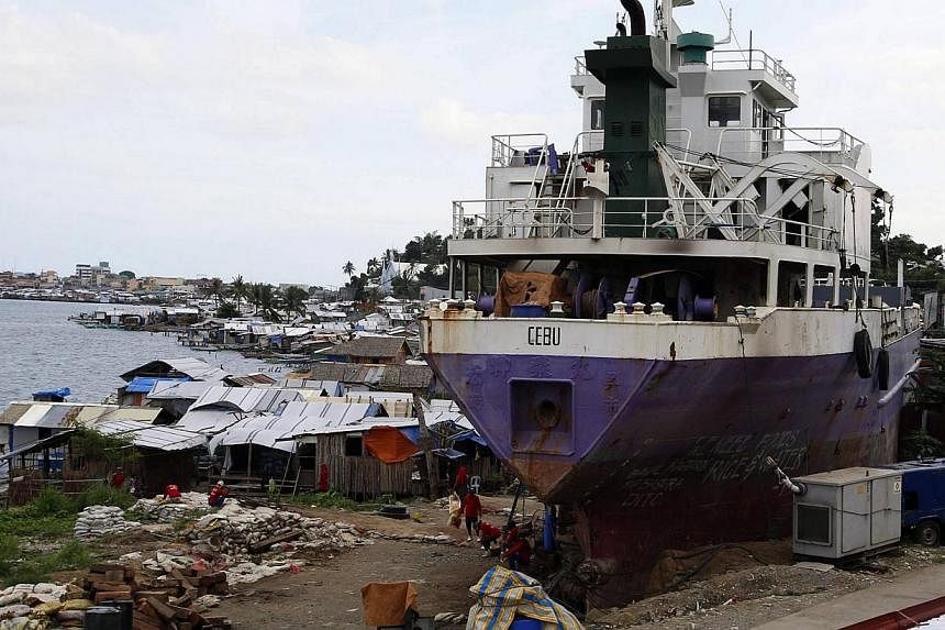 A ship which ran aground during last year's Typhoon Haiyan sits next to typhoon victims' temporary shelters in the central Philippines' Tacloban city on Nov 4, 2014. -- PHOTO: REUTERS