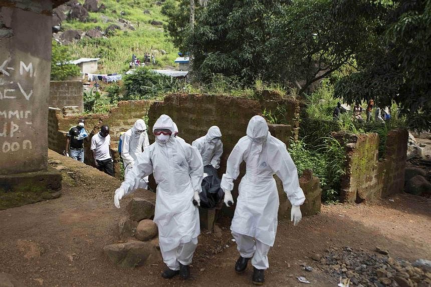 A burial team wearing protective clothing remove a body of a person suspected of having died of the Ebola virus, in Freetown Sept 28, 2014.&nbsp;Burial workers in Sierra Leone have dumped dead bodies in the street outside a hospital in protest at aut
