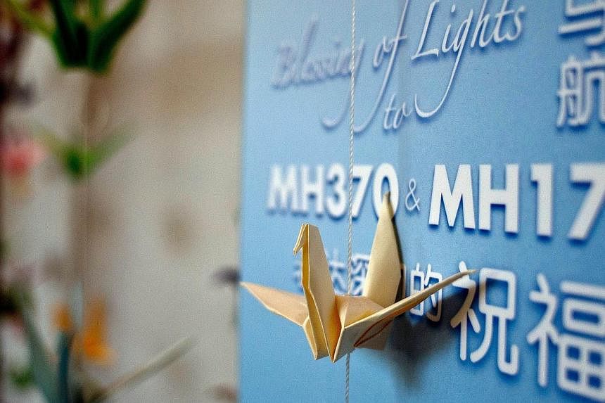 Origami paper cranes hang on a board offering prayers and condolences to the Malaysia Airlines MH370 and MH17 victims and their families at a Chinese bereavement centre in Kuala Lumpur on Sept 9, 2014.-- PHOTO: AFP