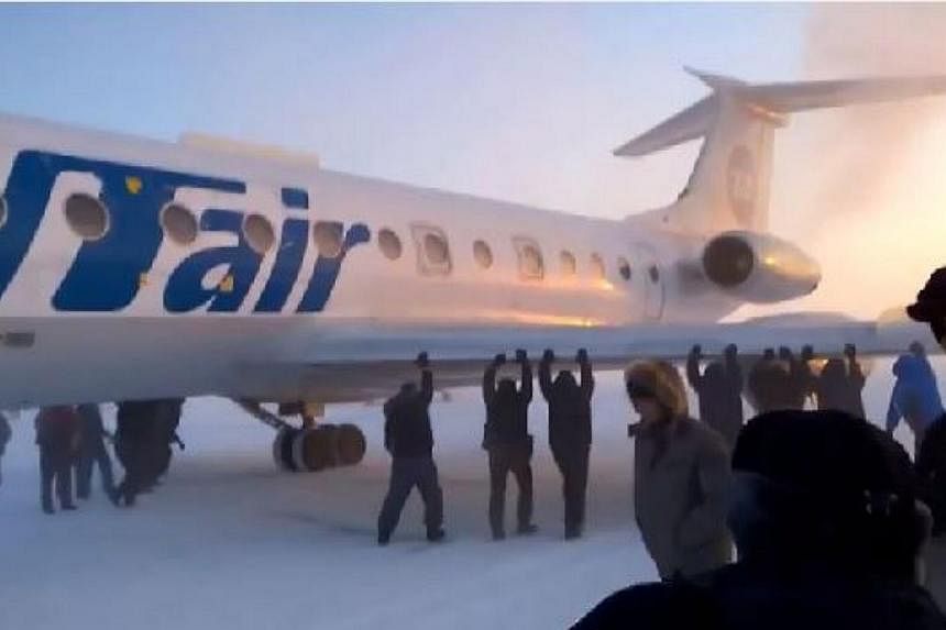 Passengers pushing the Tupolev plane on a snow-covered runway in Igarka, Russia, after its chassis froze due to temperatures of minus 52 degrees C. -- PHOTO: SCREENGRAB FROM YOUTUBE