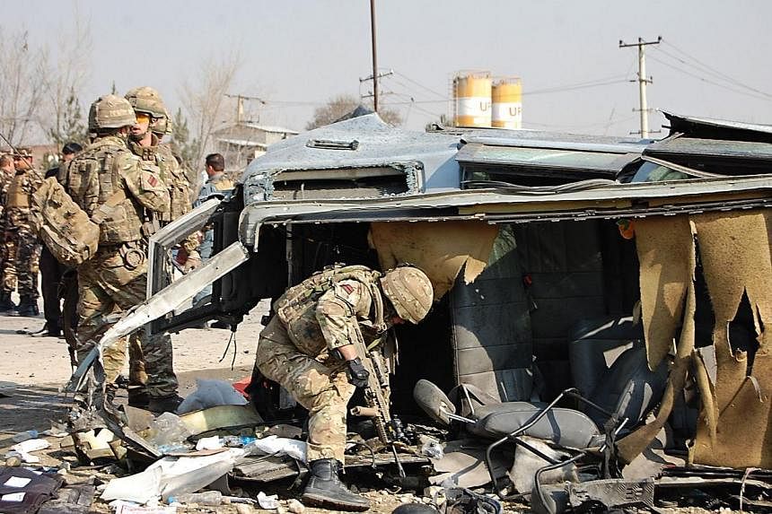 A NATO-led International Security Assistance Force (ISAF) soldier inspects a British embassy vehicle which was targeted in a suicide attack along the Kabul-Jalalabad road in Kabul on Nov 27, 2014.&nbsp;Britain said two people working for its embassy 