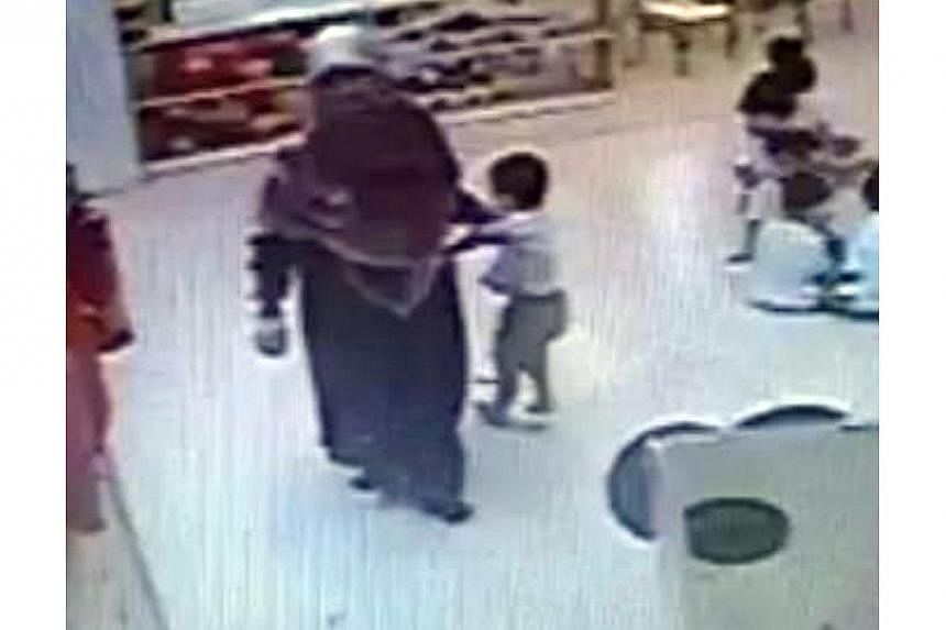 Screenshot of footage from a security camera at NTUC My First Skool in Toa Payoh, which captured childcare teacher,&nbsp;Siti Hadijah Mohamed Sin (left)&nbsp;grabbing a child by the arm when he ran towards her, before forcing him to sit. -- PHOTO: ST